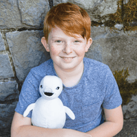 Smiling Boy Holding Stuffed Baby Beluga made from Recycled Plastic Bottles